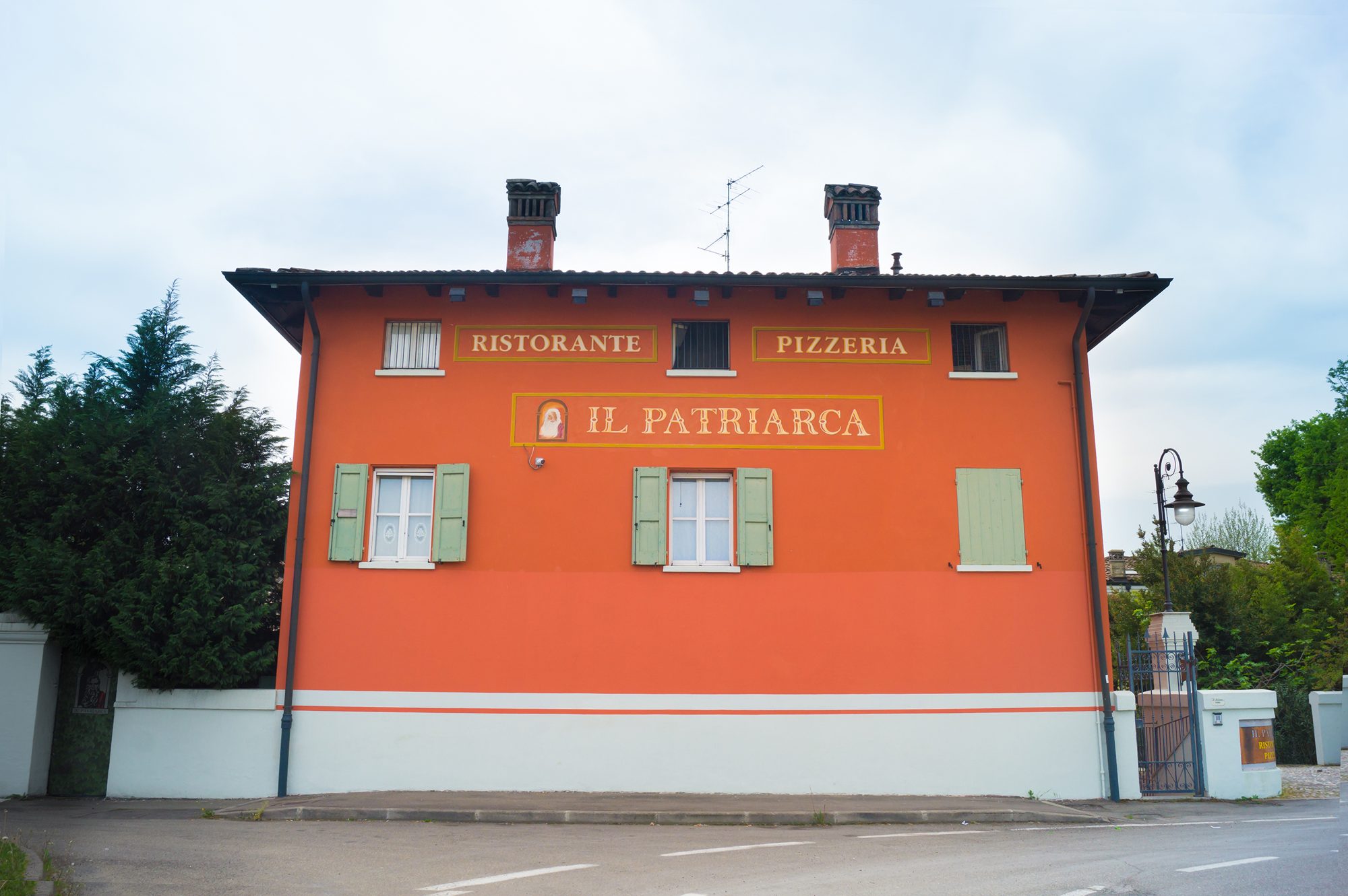 La facciata color cotto del Patriarca: il nome in oro e il medaglione del patriarca dipinti sul muro